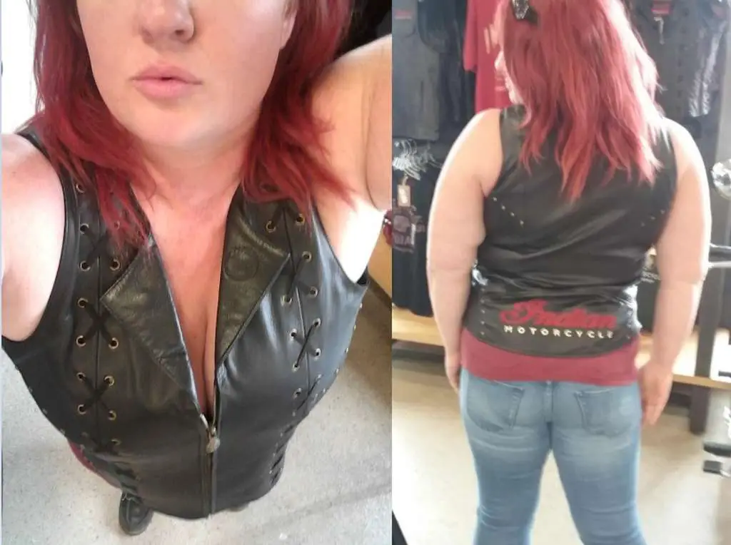Indian Women's Review, A woman with red hair is at a dealership modeling a black leather motorcycle vest embroidered with the logo 'Indian Motorcycle'. 